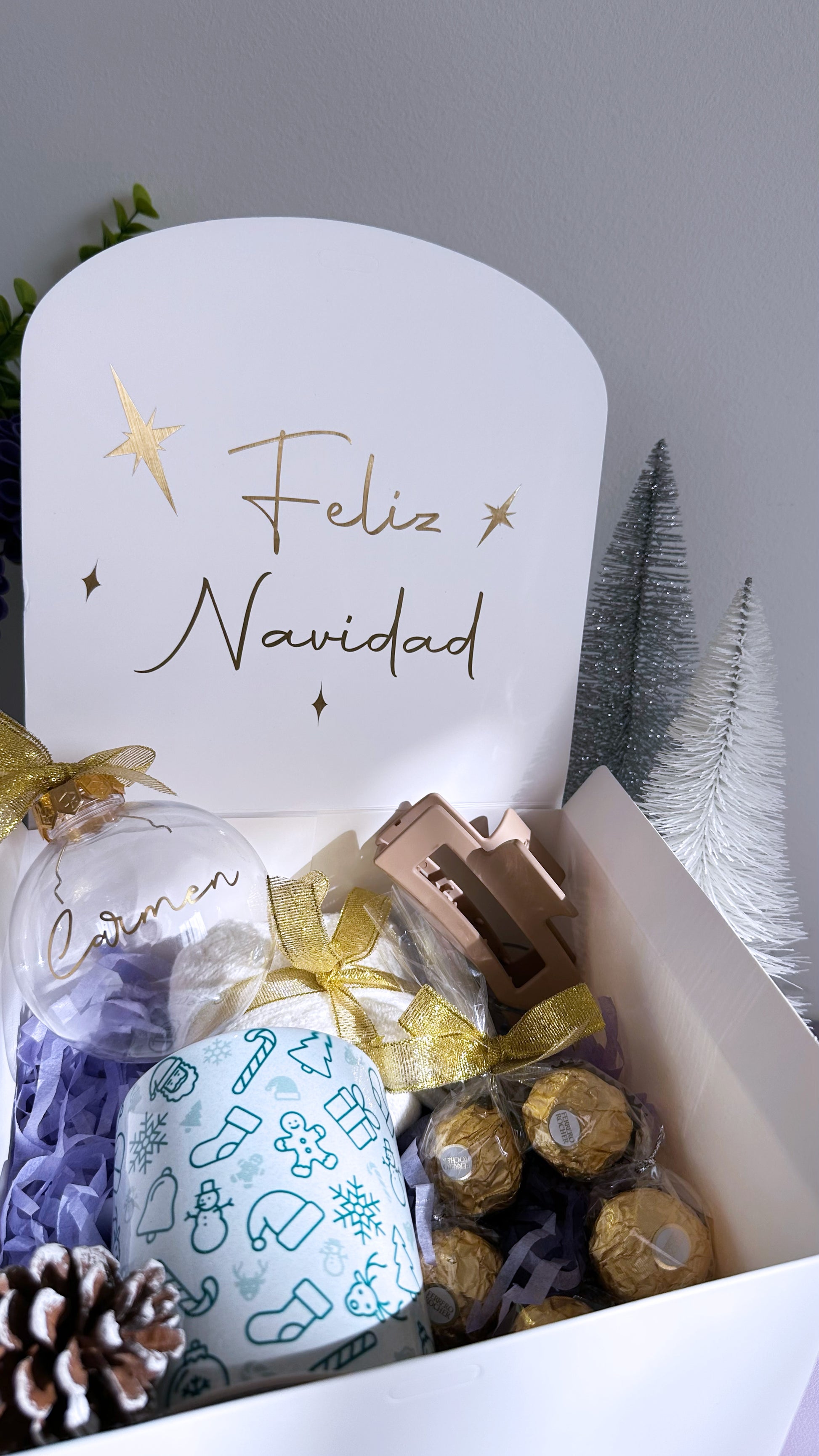 Caja regalo de Navidad personalizada – Edición acogedora abierta, con taza navideña personalizada, calcetines suaves, clip de pelo, bombones ferrero rocher y bola de Navidad personalizada con nombre. Tapa con mensaje “Feliz Navidad”.