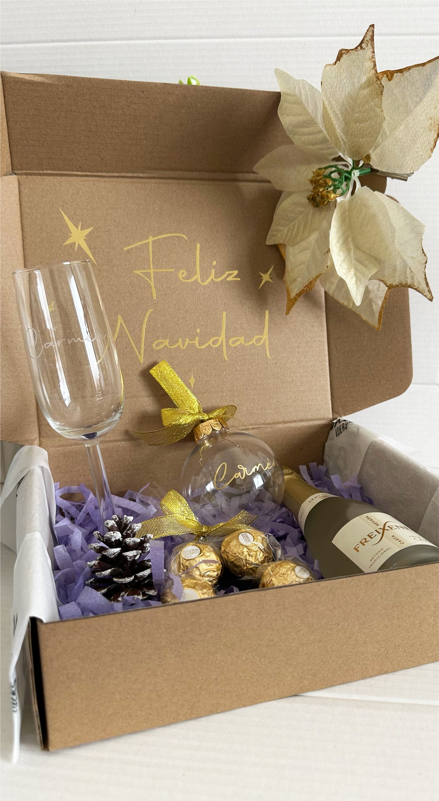 Caja regalo Navidad Brindis abierta con copa personalizada, botella de cava, bombones Ferrero Rocher y bola navideña personalizada. 